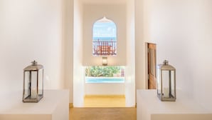 A hallway with a view of a pool and a balcony, two lanterns on pedestals, and a wooden door. - Cinnamon House by The Serendipity Collection (Weligama)