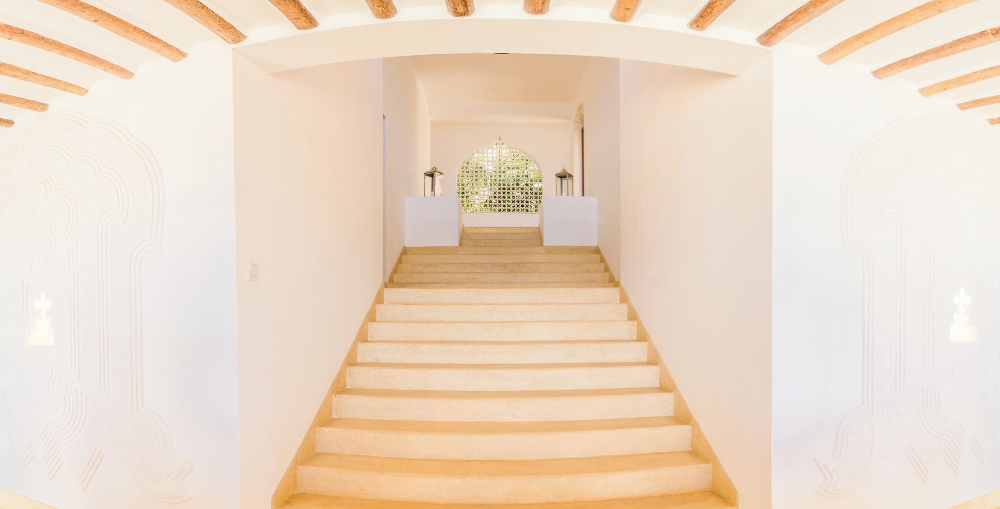 A staircase leading to a room with a decorative ceiling and a green patterned wall at the top.
