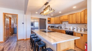Una cocina moderna con encimera de mármol, armarios de madera y un refrigerador de acero inoxidable.