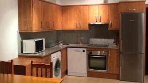 Uma cozinha moderna com armários de madeira, geladeira de aço inoxidável, micro-ondas, lava-louças e forno.