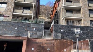 Monikerroksinen rakennus, jossa on parvekkeita, portaikko ja pysäköintialue.