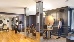 Un moderno vestíbulo de hotel con suelo de madera, un mostrador de recepción y una zona de estar con una mesa redonda y sillas.