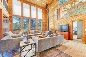 A spacious living room with large windows, a fireplace, and a television. - Howdy From Woodland West, cut Above the Clouds, (Woodland Park)