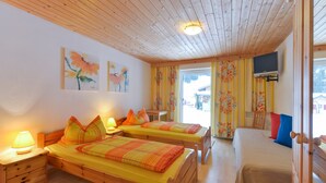 Ein Zimmer mit zwei Holzbett, einem Fernseher und Bildern an der Wand.