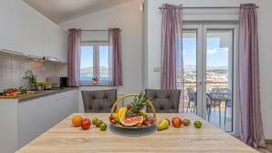 Eine moderne Küche mit Esstisch, gedeckt mit Früchten und Blick ins Freie.