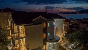 Un edificio de varios pisos con balcones, una zona de piscina y vistas al mar.