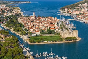 Experience the charm of a historic coastal town with a majestic castle, surrounded by a marina and lush green spaces.