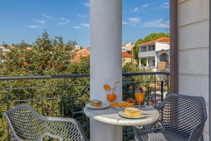 Ein Balkon mit Tisch, Stühlen und Blick auf Häuser und Bäume.