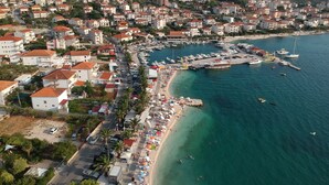 An aerial view of a coastal town with a marina, beach, and residential buildings.