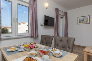 Un comedor con una mesa preparada para el desayuno, incluyendo pasteles, fruta y un tazón de cereal.