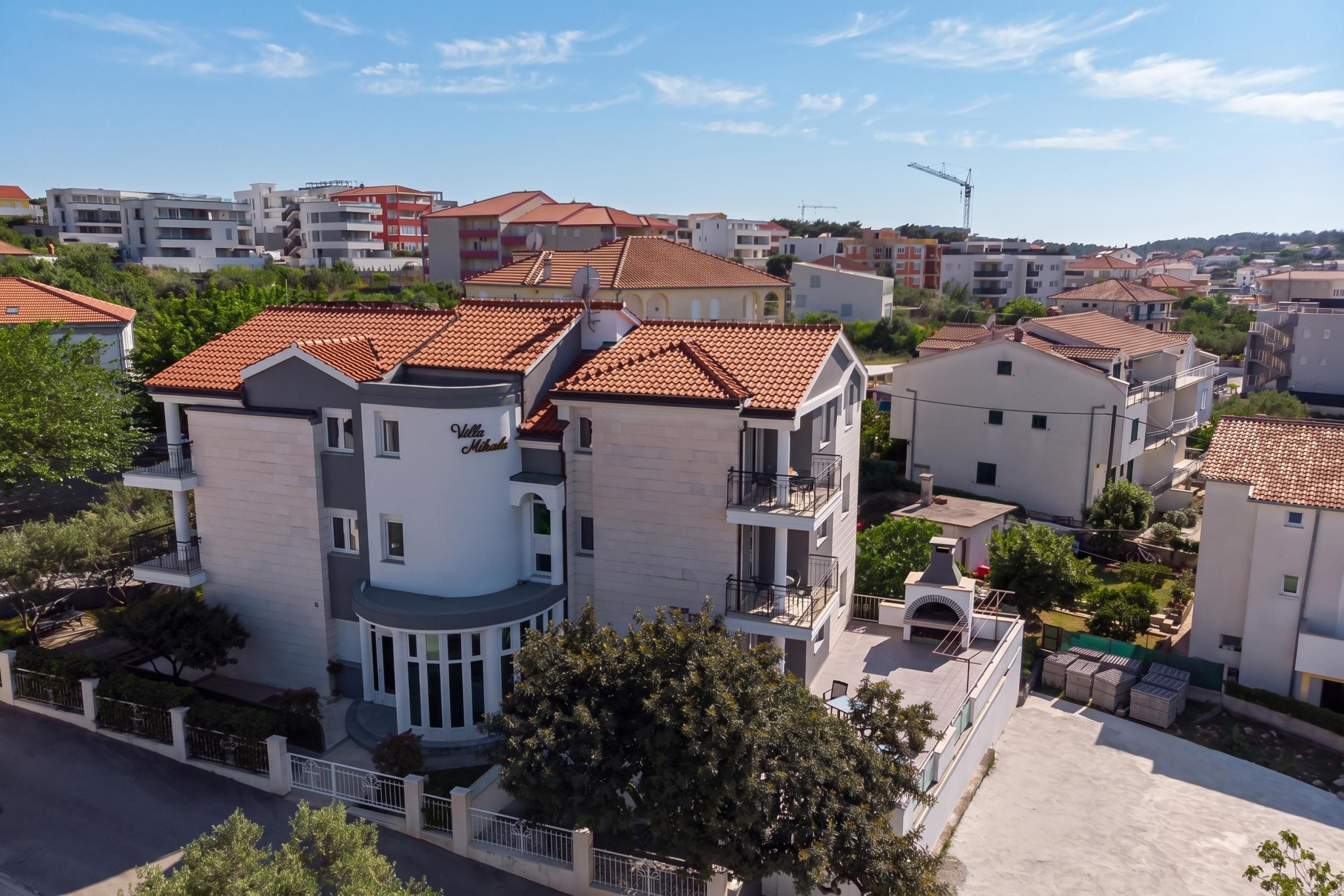 Un immeuble résidentiel à plusieurs étages, doté de balcons et d’une cour intérieure, avec une grue de construction visible à l’arrière-plan.