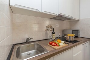 A kitchen with a stainless steel sink, a microwave, and a wooden countertop.