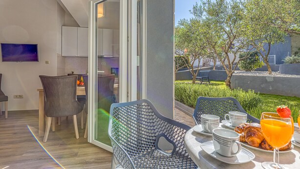 A balcony with breakfast setup including croissants, orange juice, and coffee cups. - Apartment Angie 220m from the beach, Okrug Gornji, Croatia (Okrug Gornji)