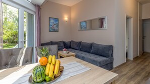 A modern living room with a grey sofa, a wooden coffee table with fruit, and a painting on the wall. - Apartment Angie 220m from the beach, Okrug Gornji, Croatia (Okrug Gornji)