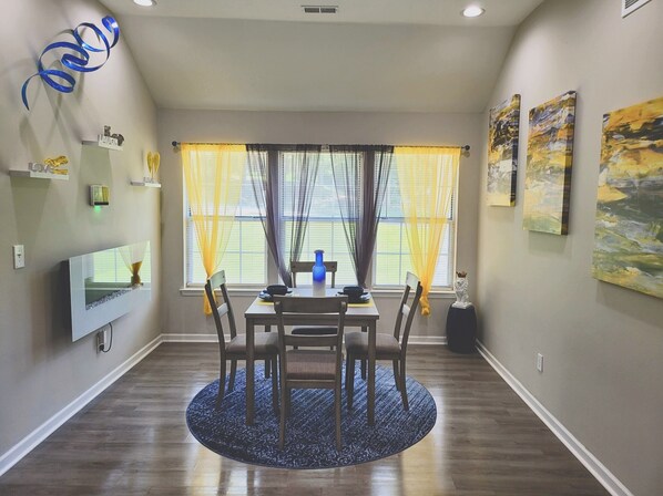 Enjoy meals in this cozy dining area with a round table and six chairs, surrounded by beautiful artwork and a stylish rug.