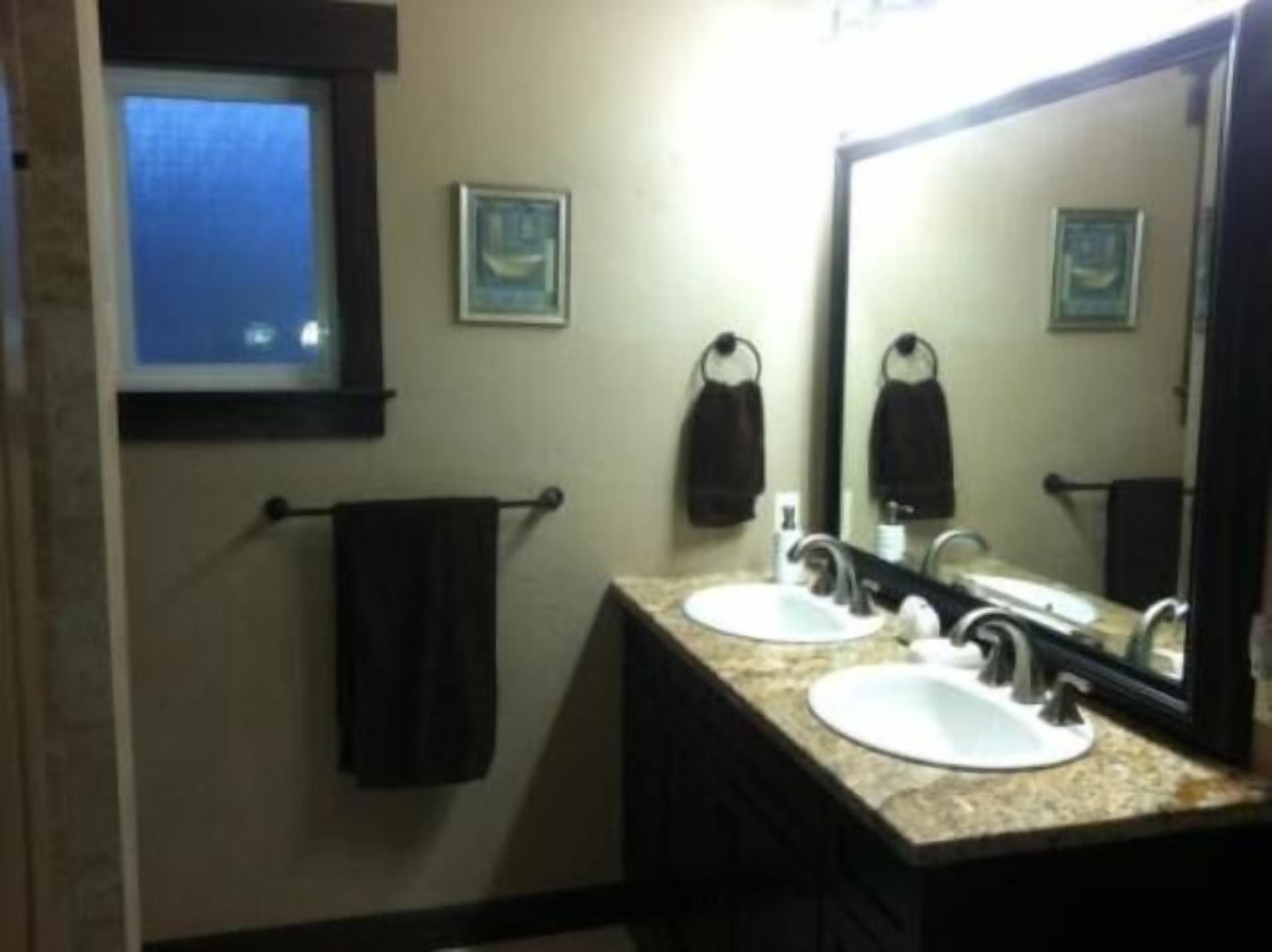 A bathroom with two sinks, a window, and a mirror.