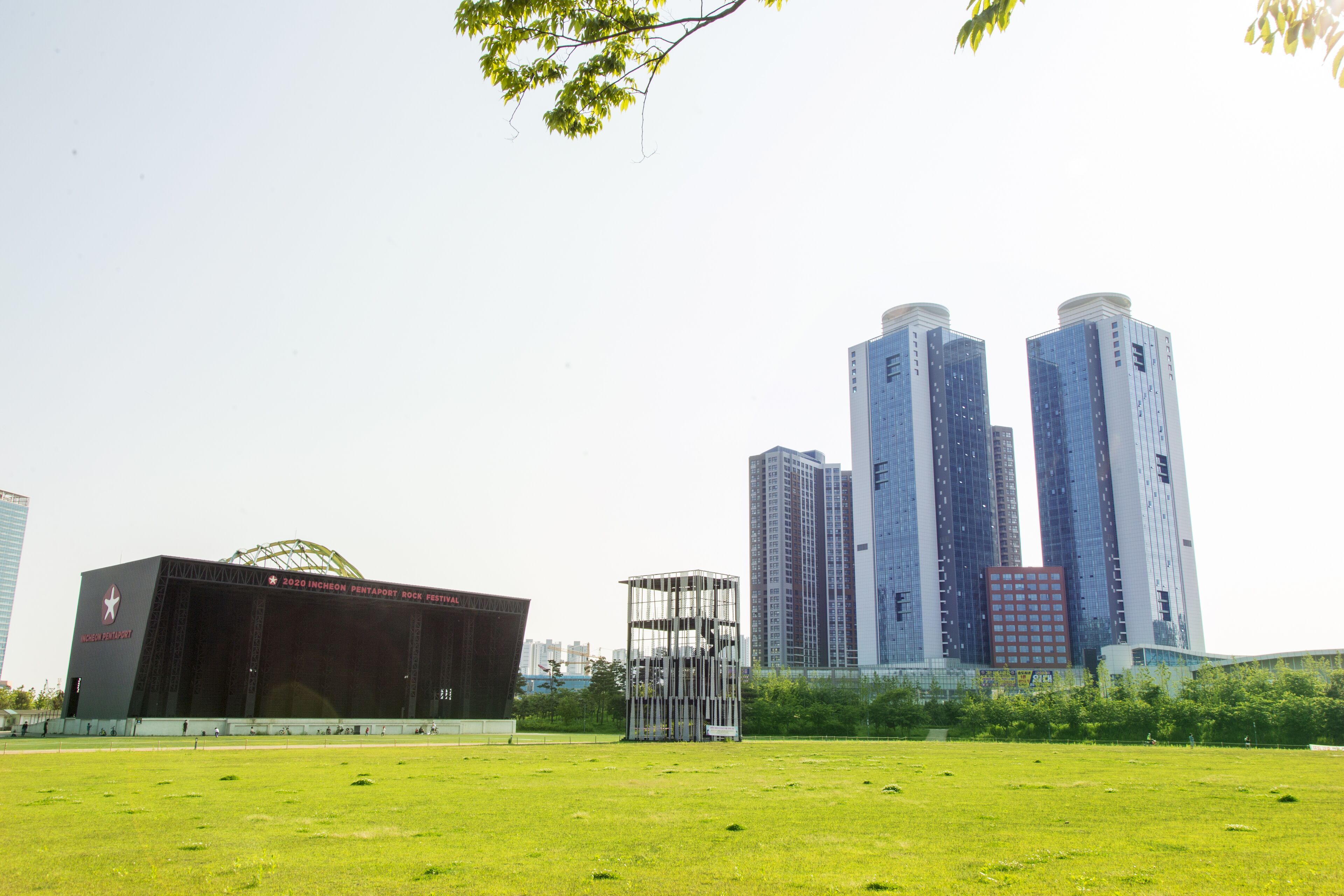 A stadium with a large open field in front, surrounded by tall buildings.