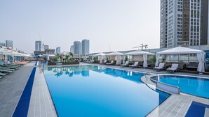 A rooftop pool with lounge chairs and umbrellas, surrounded by high-rise buildings. - Celeb Stay Songdo (Incheon)