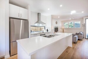 A modern kitchen with a large island, stainless steel appliances, and a built-in stove. - Yallingup Lagoon Beach House—A Spectacular Getaway (Yallingup)