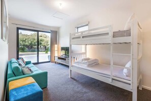 A bunk bed with a TV, a sofa with cushions, and a view of the outdoors. - Yallingup Lagoon Beach House—A Spectacular Getaway (Yallingup)