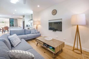 A modern living room with a sofa, coffee table, and a TV mounted on the wall. - Yallingup Lagoon Beach House—A Spectacular Getaway (Yallingup)