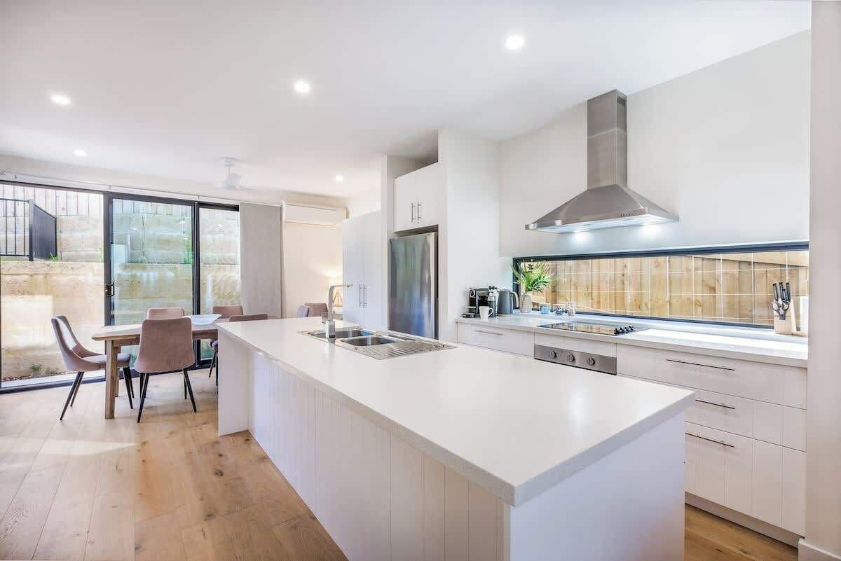 A modern kitchen with a large island, built-in appliances, and a view to the outside.