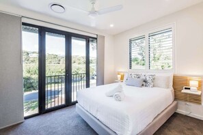 A bedroom with a large bed, a ceiling fan, a window with blinds, and a view of the outdoors. - Yallingup Lagoon Beach House—A Spectacular Getaway (Yallingup)