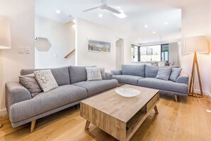 A modern living room with two grey sofas, a wooden coffee table, and a ceiling fan.