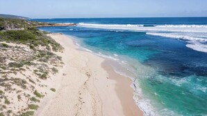 A coastal beach with clear waters and a sandy shore.