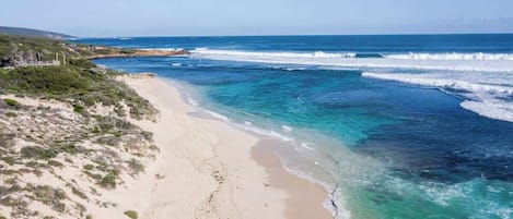 A coastal beach with clear waters and a sandy shore.