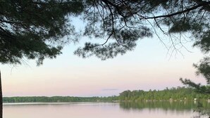 Une terrasse en bois avec un quai s’avançant dans une étendue d’eau calme, le tout entouré d’arbres.