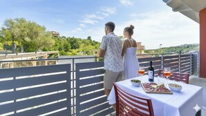 A balcony with a table set for two, overlooking a scenic landscape. - Residenza Cantalupo – Relax Oasis with Poo l Ap38 (Imperia)