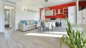 A modern apartment with a dining area, kitchenette, and a living room with a sofa and chairs. - Residenza Cantalupo – Relax Oasis with Poo l Ap38 (Imperia)