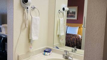 A bathroom with a white sink, a mirror, and two hair dryers mounted on the wall.