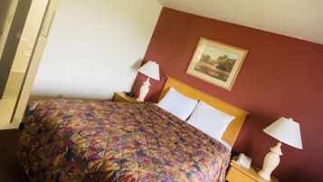 A hotel room with a large bed, two bedside lamps, a nightstand, a chair, and a painting on the wall.