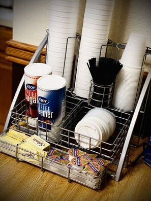 A kitchen area with a dish rack holding white plates, a coffee maker, and various food items. - Herington Inn & Suites (Herington)