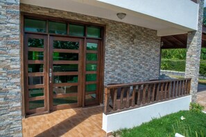 A modern building with a stone facade, large glass doors, and a wooden balcony. - Villa del Baiguate #3 (Jarabacoa)