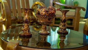 Una mesa de vidrio con candelabros ornamentados y un cuenco decorativo.