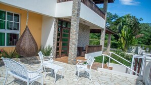 Una casa moderna con patio de piedra, mobiliario de metal blanco y una maceta colgante.