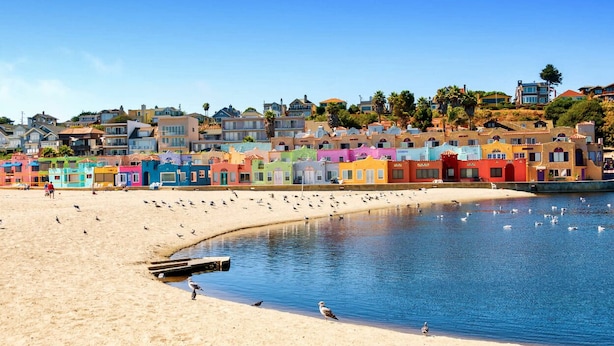 A beach with colorful houses in the background and a sandy shore.