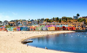 A beach with colorful houses in the background and a sandy shore.