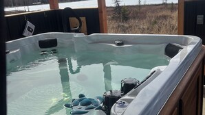 Ein Whirlpool mit freiem Blick auf einen See und Bäume im Hintergrund.