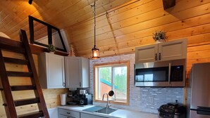 Eine moderne Küche mit Holzwänden, Edelstahlgeräten und einer Holzleiter.
