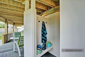 Une douche extérieure dotée d’un plafond en bois, d’un banc et d’un porte-serviettes.