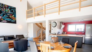 A modern loft apartment with a dining area, kitchen, and a staircase leading to an upper level.
