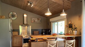 A modern kitchen with wooden cabinets, stainless steel appliances, and a large window providing natural light.