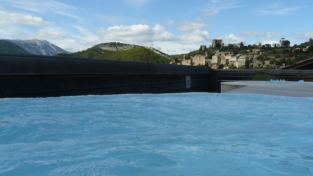 A pool with a view of a historic town and mountains in the background.