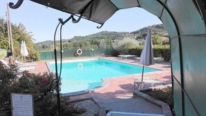 A swimming pool with lounge chairs and umbrellas, surrounded by a garden and a view of hills. - Casa delle Mammole B: A characteristic and welcoming apartment that is part of an ancient country house surrounded by the greenery, with Free WI-FI. (Citerna)
