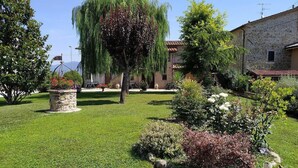 A well-maintained garden with a stone fountain, a variety of shrubs, and a large weeping willow tree. - Casa delle Mammole B: A characteristic and welcoming apartment that is part of an ancient country house surrounded by the greenery, with Free WI-FI. (Citerna)