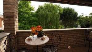 A patio with a round table and chairs, a vase of flowers, and a view of trees and a building in the background. - Casa delle Mammole B: A characteristic and welcoming apartment that is part of an ancient country house surrounded by the greenery, with Free WI-FI. (Citerna)